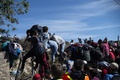 メキシコ北部ティフアナで米国境にたどり着こうとフェンスを乗り越える中米からの移民ら（2018年11月25日撮影）。(c)Pedro PARDO / AFP