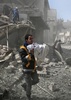 シリア首都ダマスカス近郊の東グータで行われた政府軍の爆撃で負傷し、がれきの中から救出された子どもを抱えて走る男性（2018年2月19日撮影）。(c)AFP PHOTO / ABDULMONAM EASSA