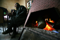 ブルガリアのBelovoにあるバーで、まきストーブで暖をとる男性（2009年1月7日撮影）。(c)AFP/BORYANA KATSAROVA
