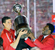 サッカーリベルタドーレス杯2010（Copa Libertadores de America 2010）は18日、決勝の第2戦がブラジルのポルトアレグレ（Porto Alegre）で行われ、インテルナシオナウ（Internacional、ブラジル）がCDグアダラハラ（Club Deportivo Guadalajara、メキシコ）を3-2で下し、2試合合計5-3で2度目の優勝を果たした。写真は優勝し、ペレ（Pele）氏からトロフィーを授与されるインテルナシオナウのファビアン・グエデス・ボリヴァル（Fabian Guedes Bolivar、左）。（2010年8月18日撮影）(c)AFP/JEFFERSON BERNARDES