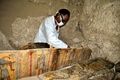 エジプト南部ルクソール近くの3500年前の墓で見つかった木棺を前に作業する考古学者（2017年4月18日撮影）。(c)AFP