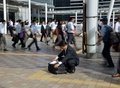 都内で、書類をチェックするためにしゃがむサラリーマン（2014年10月3日撮影）。(c)AFP/Yoshikazu TSUNO 