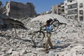シリア北部アレッポの反体制派支配地域で、空爆の後、自転車を担いでがれきの中を歩く男性（2016年9月11日撮影）。(c)AFP/AMEER ALHALBI