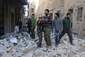 シリア北部アレッポの反体制派支配地区で、空爆により破壊されたとされる建物のがれきの上で少年を慰める男性（2016年2月4日撮影）。(c)AFP/THAER MOHAMMED