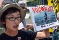 都内・国会議事堂そばで行われた安倍政権への抗議デモで、プラカードを掲げスローガンを唱えるデモ参加者（2014年7月14日撮影）。(c)AFP/Yoshikazu TSUNO