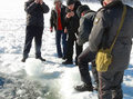 ロシア・チェリャビンスク（Chelyabinsk）州のチェバルクリ湖（Lake Chebarkul）で、表面の氷に開いた直径6メートルほどの穴のそばで小さな物体を調べる警察官たち（2013年2月15日撮影）。(c)AFP/CHELYABINSK REGION POLICE DEPARTMENT