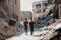シリア北部アレッポ（Aleppo）で、戦闘で建物が崩壊した通りを歩く政府軍兵士（2014年9月3日撮影）。(c)AFP