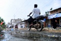 パキスタン・カラチで、ハエが群がる水たまりをバイクに乗って通り過ぎる住民（2019年8月31日撮影）。(c)RIZWAN TABASSUM / AFP