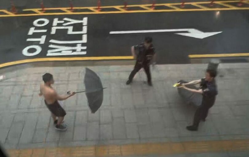 拳を構えて警察官に殴りかかり、傘を使って抵抗する男＝読者提供(c)NEWSIS