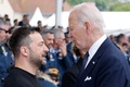 Dデー80年の記念式典が開催された仏ノルマンディーで、言葉を交わすウクライナのウォロディミル・ゼレンスキー大統領（左）と米国のジョー・バイデン大統領（中央、2024年6月6日撮影）。(c)Ludovic MARIN / POOL / AFP