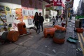 香港の旺角地区で、違法屋台の取り締まりに抗議する人と警官隊の衝突でごみ箱の中身などが散乱した通りを歩く人（2016年2月9日撮影）。(c)AFP/DALE DE LA REY