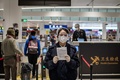 中国・北京の空港で、新型コロナウイルス「COVID-19」の流行を受け、到着した乗客らに医療関係の文書への記入と署名を求める検疫官（2020年2月14日撮影）。(c)NICOLAS ASFOURI / AFP