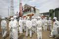 東京電力（TEPCO）は26日、福島第1原子力発電所の敷地内を報道陣に公開した。写真は第1原発4号機を取材する報道陣と東電従業員（2012年5月26日撮影）。(c)AFP/POOL/Tomohiro Ohsumi