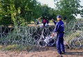 ハンガリーとセルビアの国境に設置された有刺鉄線を挟んで、移民らに指示するハンガリーの警察官（2015年8月27日撮影）。(c)AFP/ATTILA KISBENEDEK