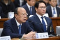 韓国・朴槿恵（パク・クネ）大統領の親友による国政介入疑惑に絡み、国会の聴聞会に呼ばれて証言するハンファグループ会長の金升淵（キム・スンヨン）氏とそれを聞くSKグループ会長の崔泰源（チェ・テウォン）氏（2016年12月6日撮影）。(c)AFP/JUNG YEON-JE