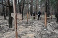 ウクライナ・イジューム近郊の森で見つかった集団墓地で、捜査を行うウクライナ警官（2022年9月16日撮影）。(c)SERGEY BOBOK / AFP