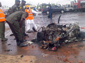 ナイジェリアの首都アブジャ（Abuja）の警察本部で、自爆攻撃による爆発の被害を受けた車を調べる警官（2011年6月16日撮影）。(c)AFP/NEMA