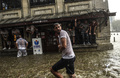 トルコの最大都市イスタンブールで、激しい雨とひょうが降る中、建物の軒先に避難する人々の前を歩く人（2017年7月27日撮影）。(c)AFP/Bulent KILIC