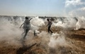 パレスチナ自治区ガザ地区のイスラエルとの境界付近で行われたデモで、イスラエル軍が発射した催涙ガス弾から逃げるパレスチナ人（2018年6月8日撮影）。(c)AFP PHOTO / MAHMUD HAMS