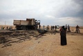 シリア北部ジャラブルス近郊で、イスラム過激派組織「イスラム国（IS）」のアブハッサン・ムハージル報道担当者が殺害された現場とされる場所に残る焼け焦げたトラックの周囲に集まる住民ら（2019年10月27日撮影）。(c)Aaref WATAD / AFP