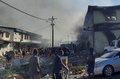 ソロモン諸島の首都ホニアラの中華街で、燃やされた建物から立ち上る煙を見る人々（2021年11月26日撮影）。(c)CHARLEY PIRINGI / AFP