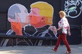 リトアニアの首都ビリニュスで、キスをするドナルド・トランプ氏とウラジーミル・プーチン大統領が描かれた壁画の前を歩く女性（2016年5月13日撮影）。(c)AFP/Petras Malukas 