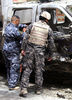 イラクの首都バグダッド（Baghdad）で起きた自動車爆弾攻撃の現場で、損傷した車を調べる警察官（2013年5月30日撮影）。(c)AFP/AHMAD AL-RUBAYE