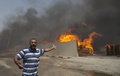 パレスチナ自治区ガザ地区（Gaza Strip）で、イスラエル軍の攻撃で炎上する国連（UN）倉庫と、そばで感情をあらわにするパレスチナ人男性（2014年7月12日撮影）。(c)AFP/MAHMUD HAMS