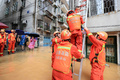 豪雨による洪水に見舞われた中国湖南省衡陽市で、建物の中から子どもを避難させる救助隊員ら（2019年7月9日撮影）。(c)STR / AFP