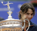 男子テニス、バルセロナ・オープン・バンコ・サバデル（%%Barcelona Open Banco Sabadell 2009%%）シングルス決勝。大会第1シードのラファエル・ナダル（%%Rafael Nadal%%、スペイン）は、大会第4シードのダビド・フェレール（%%David Ferrer%%、スペイン）と対戦。ナダルはセットカウント2-0（6-2、7-5）のストレートで勝利し、大会5連覇を達成した。写真は優勝を果たし、トロフィーをかむラファエル・ナダル。（2009年4月26日撮影）(c)AFP/JOSEP LAGO