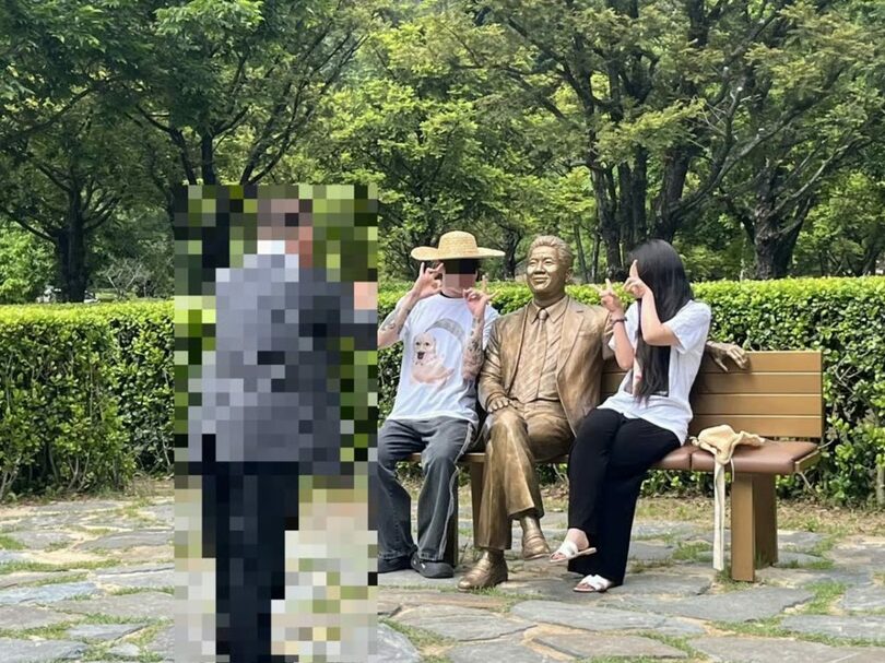 故ノ・ムヒョン（盧武鉉）元大統領の17周忌追悼式で、「イルベ」を意味する指のポーズを取って写真を撮る人物(c)MONEYTODAY