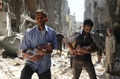 シリア北部アレッポの反体制派支配地域で、空爆の後、赤ちゃんを抱いてがれきの中を逃げる2人の男性（2016年9月11日撮影）。(c)AFP/AMEER ALHALBI
