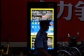 中国・上海で、路上に設置された顔認証スクリーンの前を歩く警察官（2017年8月9日撮影）。(c)CHANDAN KHANNA / AFP