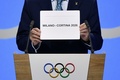 スイス・ローザンヌで行われた国際オリンピック委員会（IOC）総会で、2026年冬季五輪の開催地としてイタリアのミラノ・コルティナダンペッツォの名前が書かれたカードを掲げるIOCのトーマス・バッハ会長（2019年6月24日撮影）。(c)Fabrice COFFRINI / AFP