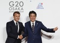 大阪で開催中の20か国・地域（G20）首脳会議の歓迎行事で、エマニュエル・マクロン仏大統領（左）を迎える安倍晋三首相（右、2019年6月28日撮影）。(c)KIM KYUNG-HOON / POOL / AFP
