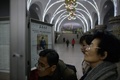 北朝鮮・平壌の地下鉄駅で、金正恩朝鮮労働党委員長が代議員選挙に投票する写真が掲載された労働新聞を見る人々（2019年3月11日撮影）。(c)Ed JONES / AFP