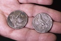 ユダヤ砂漠にあるムラバアト洞窟の発掘現場で見つかった銀貨15枚のうちの2枚。出土した筒の中に入っていた。ヘレニズム時代のエジプト王、プトレマイオス6世フィロメトルの肖像があしらわれている（2022年12月13日撮影）。(c)MENAHEM KAHANA / AFP