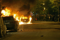 ギリシャの首都アテネ（Athens）で、火を放たれた車をながめる抗議デモの参加者（2008年12月9日撮影）。(c)AFP
