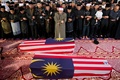 マレーシア・クアラルンプール（Kuala Lumpur）郊外のプトラジャヤ（Putrajaya）で、ウクライナ東部で撃墜されたとされるマレーシア航空（Malaysia Airlines）MH17便の副操縦士だった男性と客室乗務員だった女性の遺体を納めたひつぎの前で祈りを捧げる遺族たち（2014年8月22日撮影）。(c)AFP/MOHD RASFAN