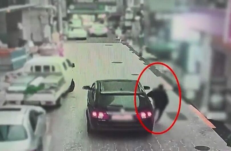 走行中の車に故意に体を接触させる様子＝釜山警察庁提供(c)NEWSIS