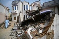 パキスタンのミルプール近郊で、地震で倒壊した家の横を通る人（2019年9月25日撮影）。(c)AAMIR QURESHI / AFP