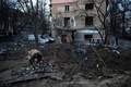 ウクライナの首都キーウで、ロシアの攻撃でできた穴からミサイルの破片を集める兵士（2022年12月31日撮影）。(c)SERGEI CHUZAVKOV / AFP