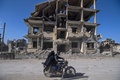 シリア北部ラッカにある破壊された建物の前をバイクで通るカップル（2019年2月19日撮影）。(c)AFP / Fadel Senna