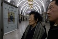 北朝鮮・平壌の地下鉄駅で、金正恩朝鮮労働党委員長が代議員選挙に投票する写真が掲載された労働新聞を見る人々（2019年3月11日撮影）。(c)Ed JONES / AFP
