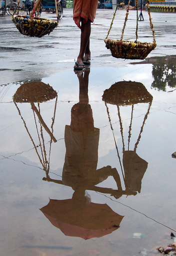 水たまりに映る露天商の影