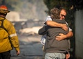米カリフォルニア州グラナダヒルズで、サドルリッジ森林火災で自宅を焼失した隣人を慰める男性（2019年10月11日撮影）。(c)Josh Edelson / AFP