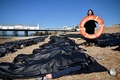 英南部ブライトンの海岸で、地中海の難民船問題をめぐる英政府の対応を非難する国際人権団体アムネスティ・インターナショナルが抗議行動の一環として並べた遺体袋（2015年4月22日撮影）。(c)AFP/BEN STANSALL