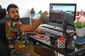 米国人アーティスト、ビープルのデジタルコラージュ作品（画面内）を非代替性トークン（NFT）として6930万ドル（約75億円）で落札したビグネシュ・スンダレサン氏（2021年4月7日撮影）。(c)Roslan RAHMAN / AFP