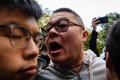 香港立法会（議会）の補欠選挙で、民主派の活動家、黄之鋒（ジョシュア・ウォン）氏（左）の耳元で叫ぶ男性（2018年3月11日撮影）。(c)AFP PHOTO / ANTHONY WALLACE