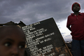 2007年10月24日、ケニヤのスラム街キベラ（Kibera）で、母親の生薬店の前に立つ男の子たち。(c)AFP/Roberto SCHMIDT